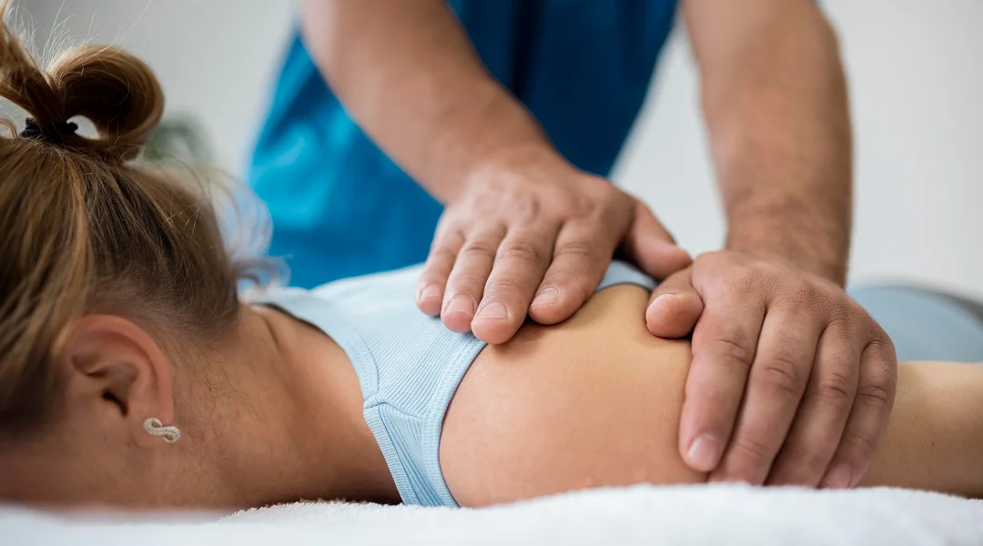 Une femme reçoit un massage du dos dans le cadre d'une séance de fasciathérapie.