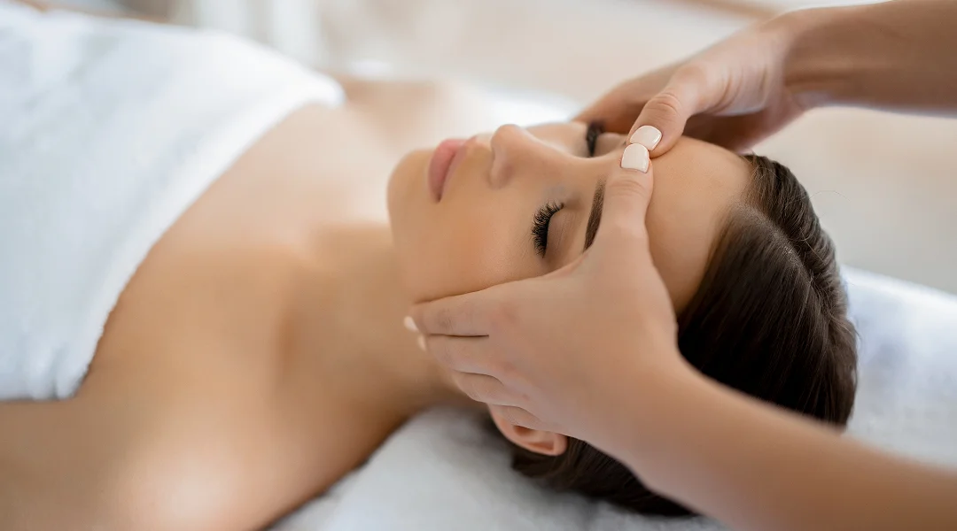 Une femme reçoit un massage facial dans un spa, visant à soulager les migraines.