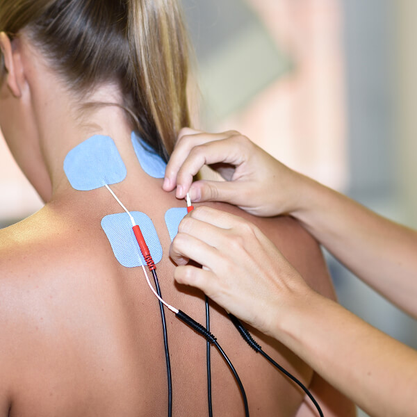 Une femme utilise un appareil électrique pour soulager des douleurs au dos.